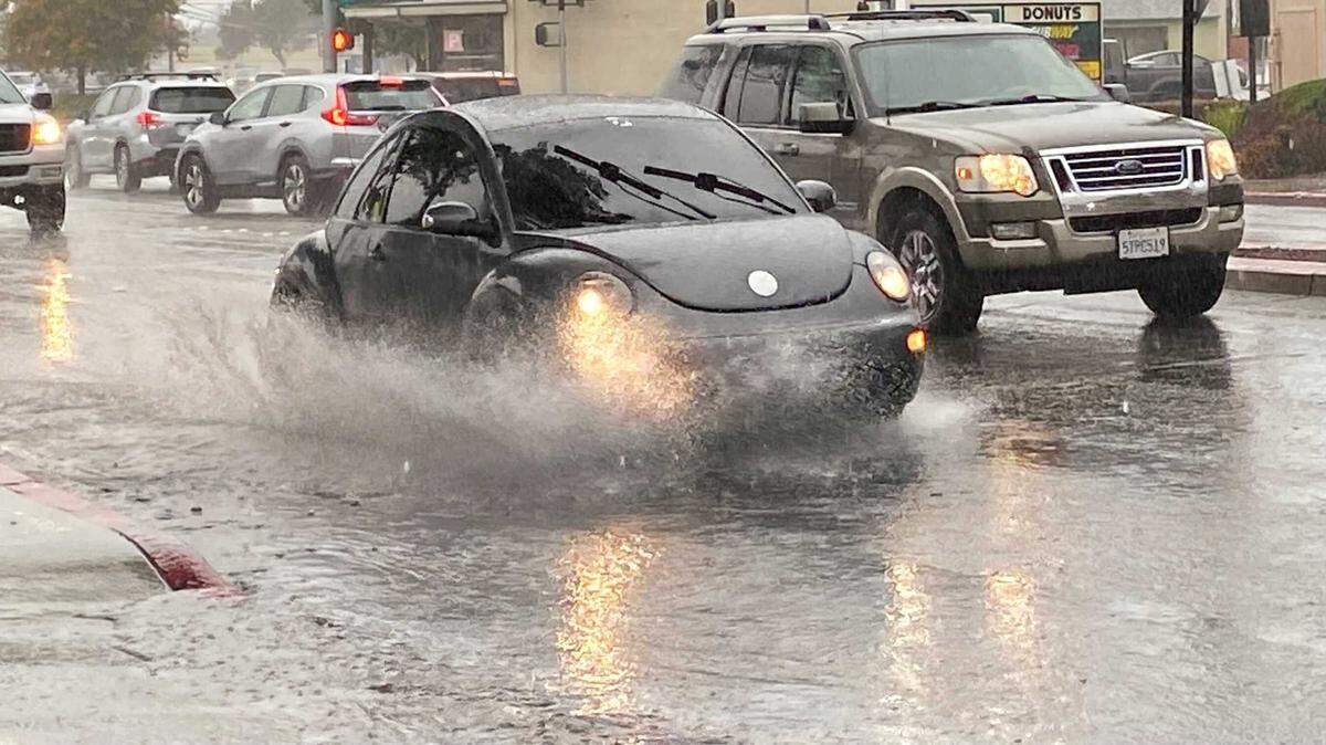 Cars splash through overflowing gutters as rain falls on East Grand Avenue in Arroyo Grande near Halcyon Road.