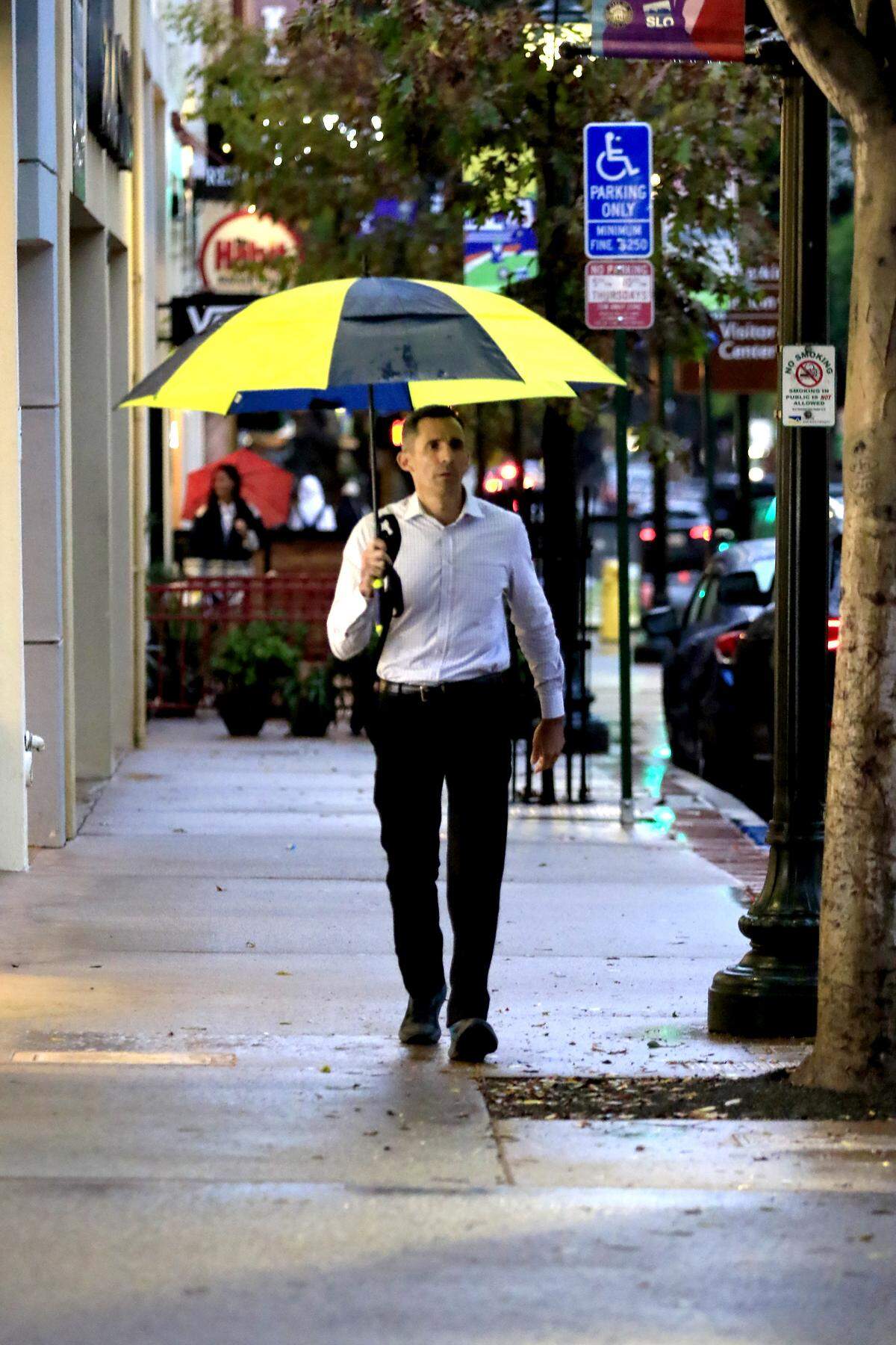 A man sports a colorful umbrella while walking through downtown San Luis Obispo during a rain storm on Nov. 13, 2025.