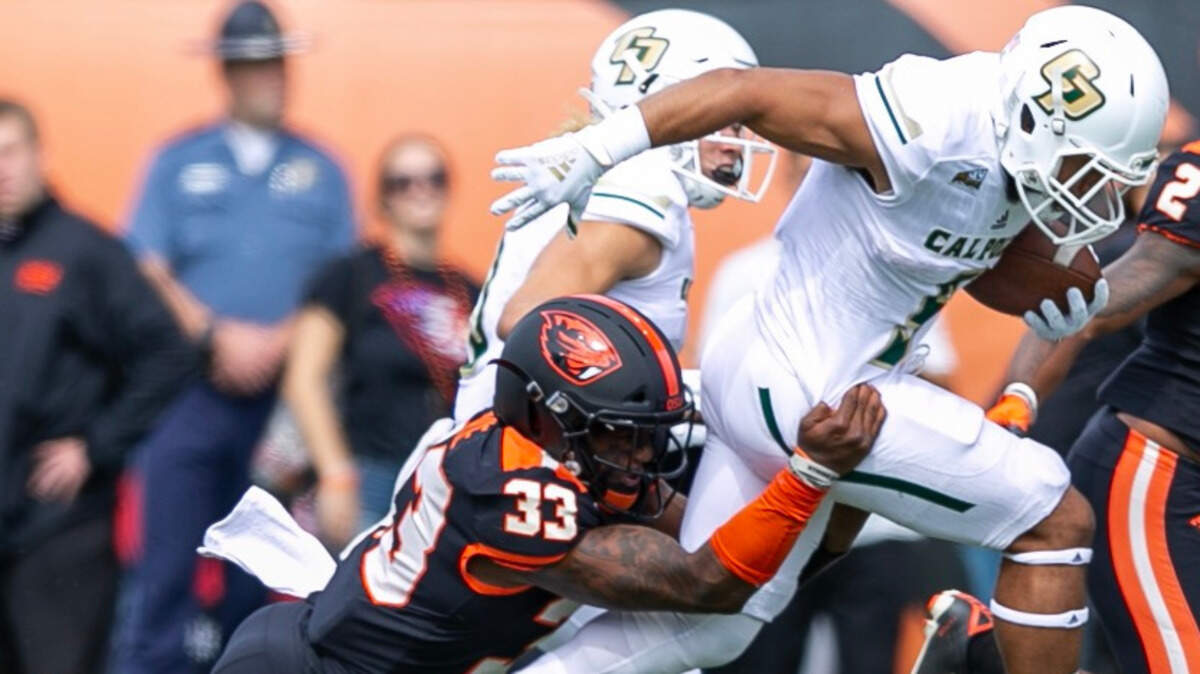 Cal Poly running back Lepi Lataimua runs as Oregon State’s Jalen Moore tries to bring him down.