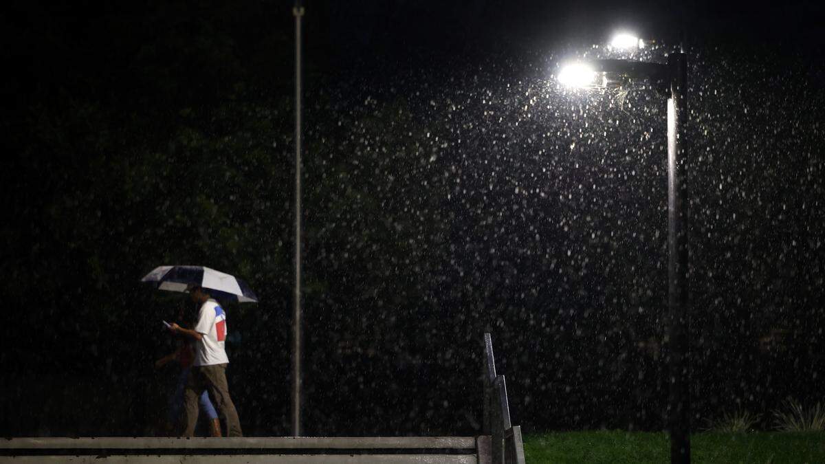 A couple shares an umbrella as rain falls in front of the Kennedy Library at Cal Poly on Nov. 13, 2025.