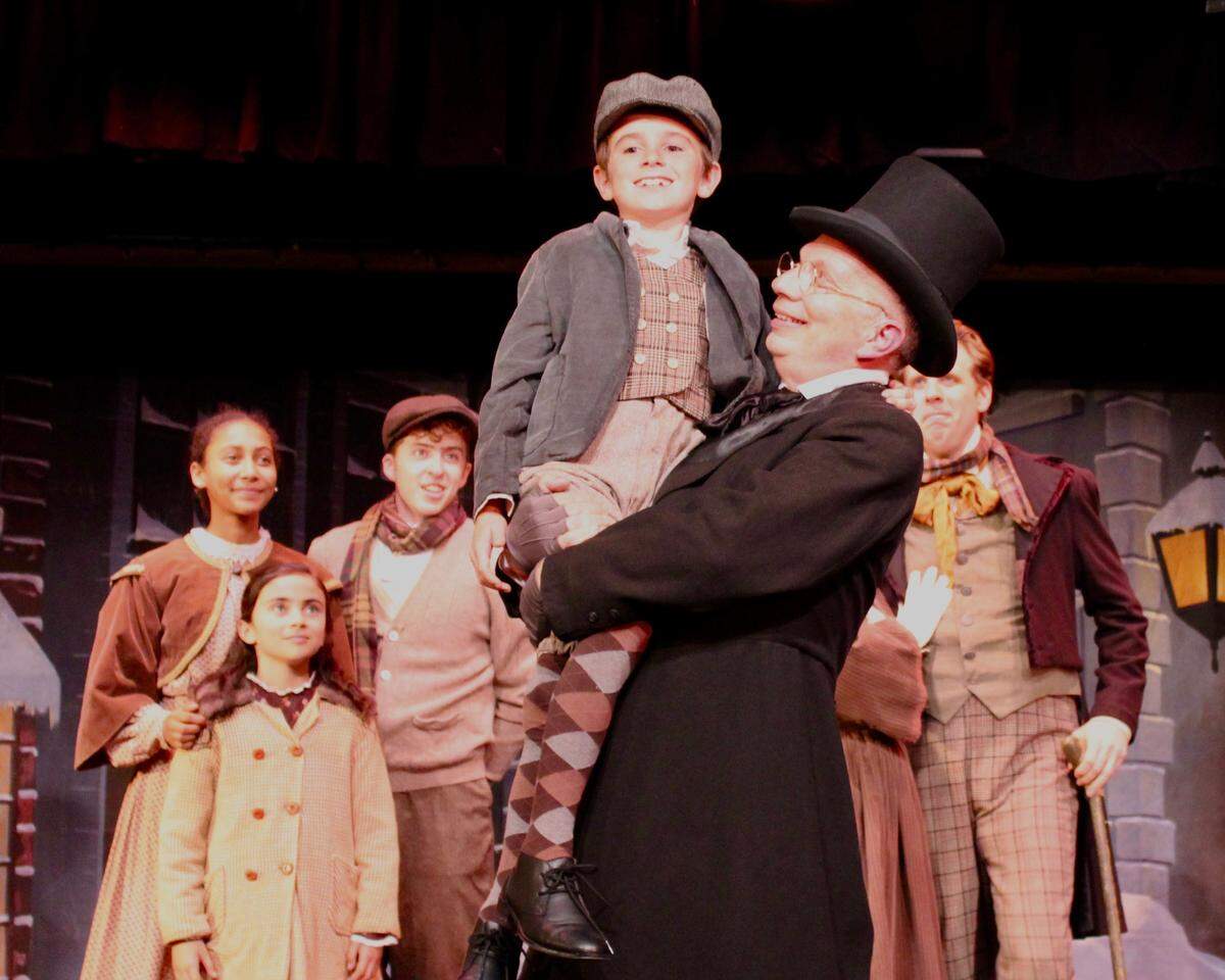 Ebenezer Scrooge (Billy Breed), center, lifts up Tiny Tim (Corbin Brown) in a scene from “A Christmas Carol,” playing as part of “The Holiday Extravaganza” through Dec. 31 at the Great American Vaudeville & Melodrama in Oceano.