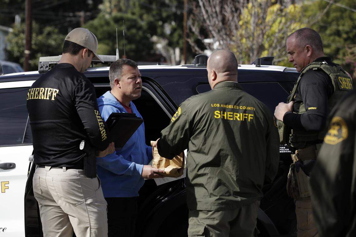 Paul Flores, second from left, talks to authorities after being pulled from a Los Angeles County Sheriff’s Department vehicle outside of a San Pedro home being searched in connection with the Kristin Smart case on Wednesday, Feb. 5, 2020, in Los Angeles. Search warrants were served at locations in California and Washington state in the search for the Cal Poly student who disappeared in 1996.