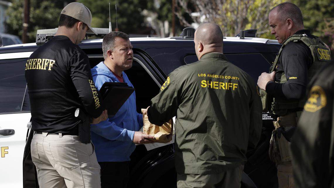 Paul Flores, second from left, talks to authorities after being pulled from a Los Angeles County Sheriff’s Department vehicle outside of a San Pedro home being searched in connection with the case Wednesday, Feb. 5, 2020, in Los Angeles. Search warrants were served Wednesday at locations in California and Washington state in the investigation of the disappearance of Kristin Smart, the Cal Poly student who disappeared in 1996.