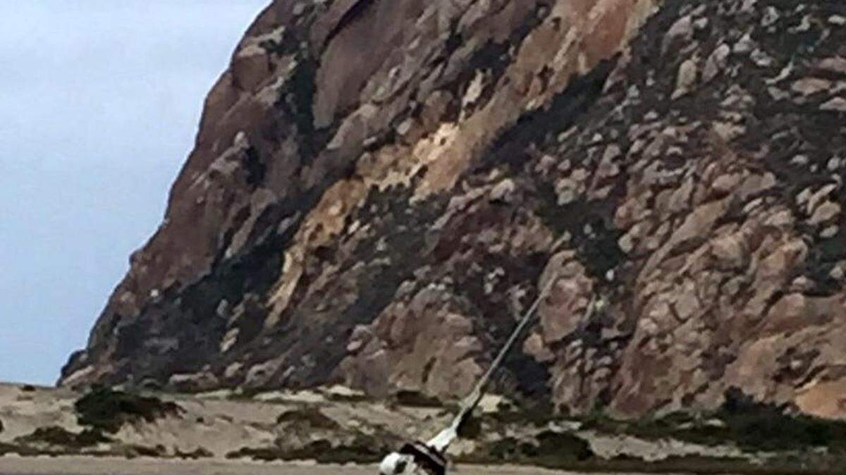 The 20-foot-long sailboat, named the Good News, is beached on the sand spit in Morro Bay.