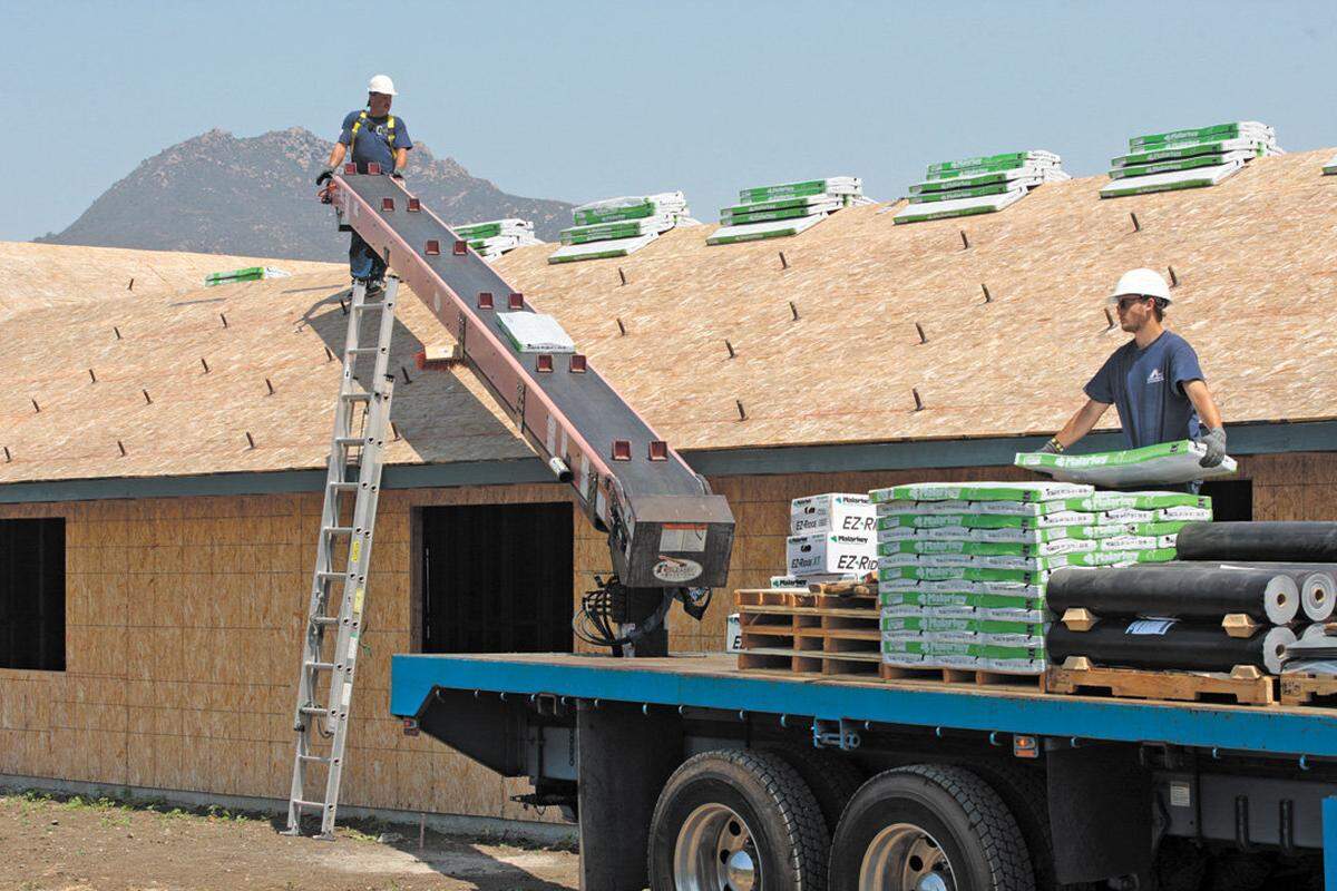 Shawn Clark, left, and Tate Jimeson with R & S Supply set up roofing materials as construction at Sunny Acres continues in 2015.