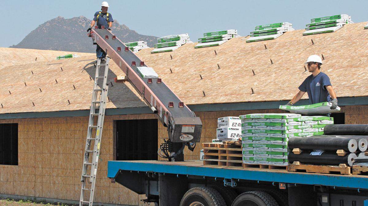 Shawn Clark, left, and Tate Jimeson with R&S Supply set up roofing materials during construction of a sober-living building at Dan DeVaul’s Sunny Acres property in 2015.