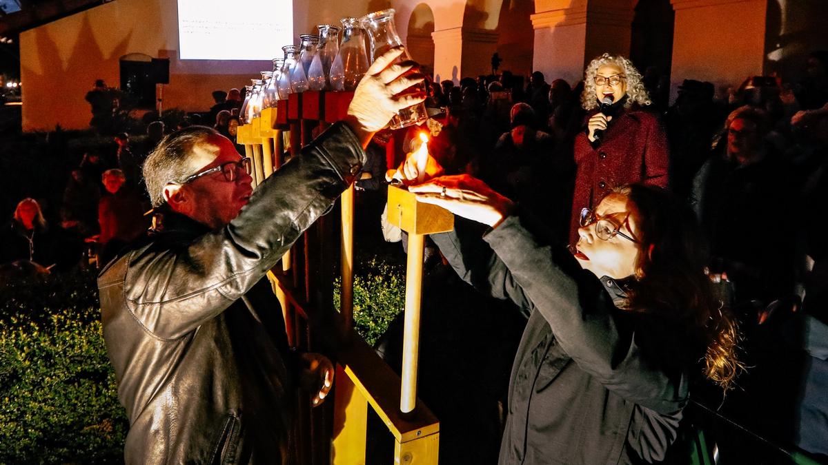 Supervisor Adam Hill and Morro Bay City Council member Dawn Addis light the shamash, the candle used to light the menorah. Rabbi Janice Mehring, right, looks on with other community members who gathered in Mission Plaza to celebrate the first night of Hanukkah in 2018.