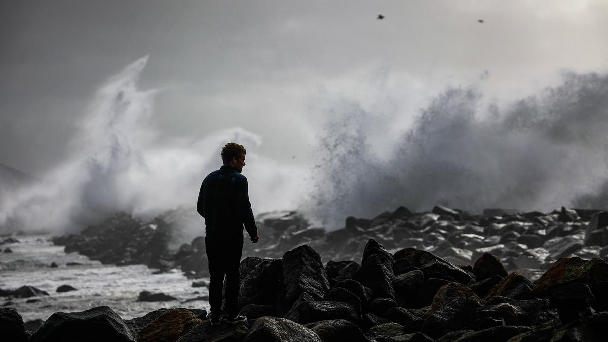 A young man watches the big surf break over the jetty in Morro Bay on Thursday.