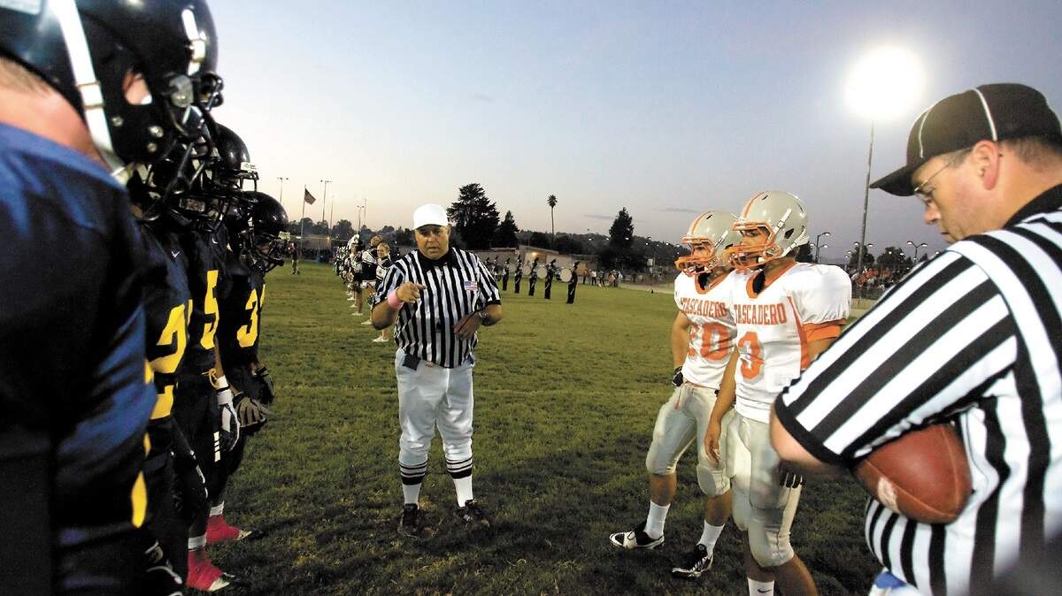 Referee Bobby Kennedy, center, and umpire Patric Earnest, right, meet with captains from Arroyo Grande and Atascadero highs for the flip of the coin before their PAC 7 game Oct. 1 in Arroyo Grande.