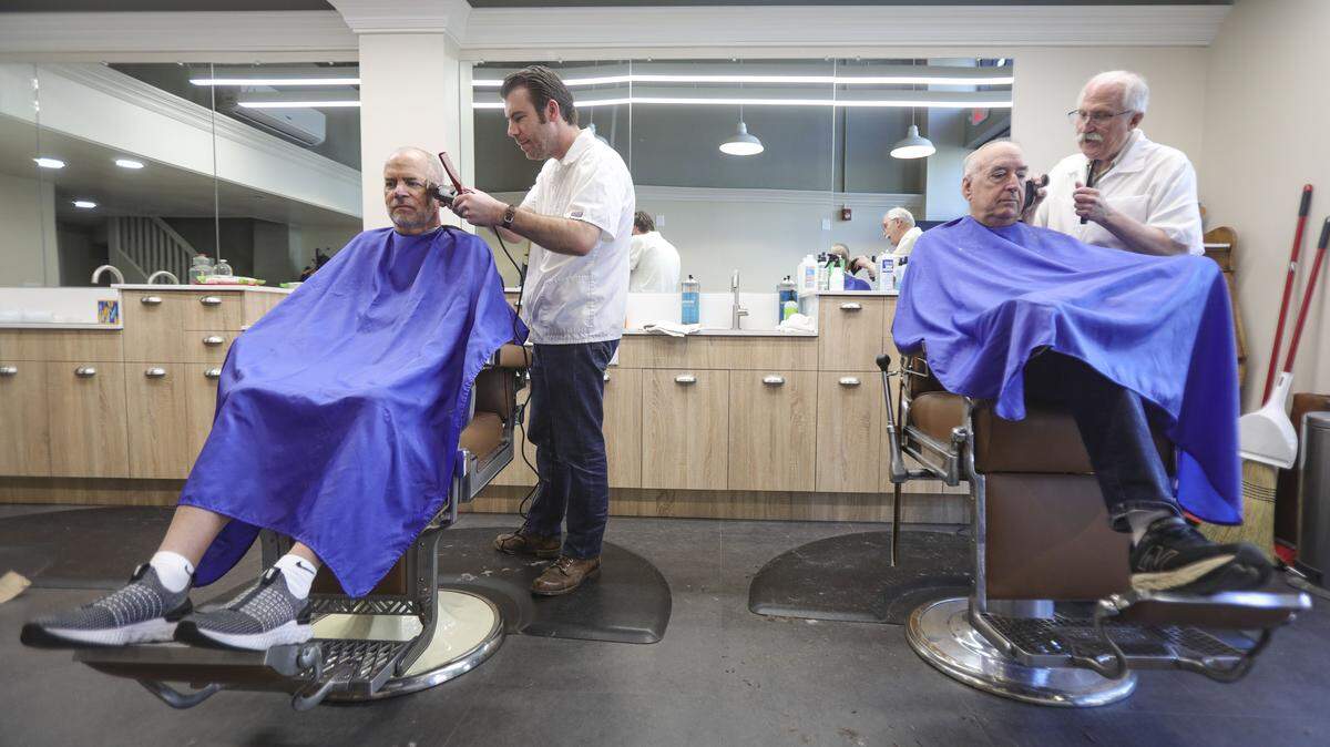 Barbers Ben Fleming, left and Ray Shearer give haircuts to Tom Dorich, left, and Michael Kennedy. The Anderson Barber Shop has moved back to its original location on Monterey Street, seen here on April 7, 2026.