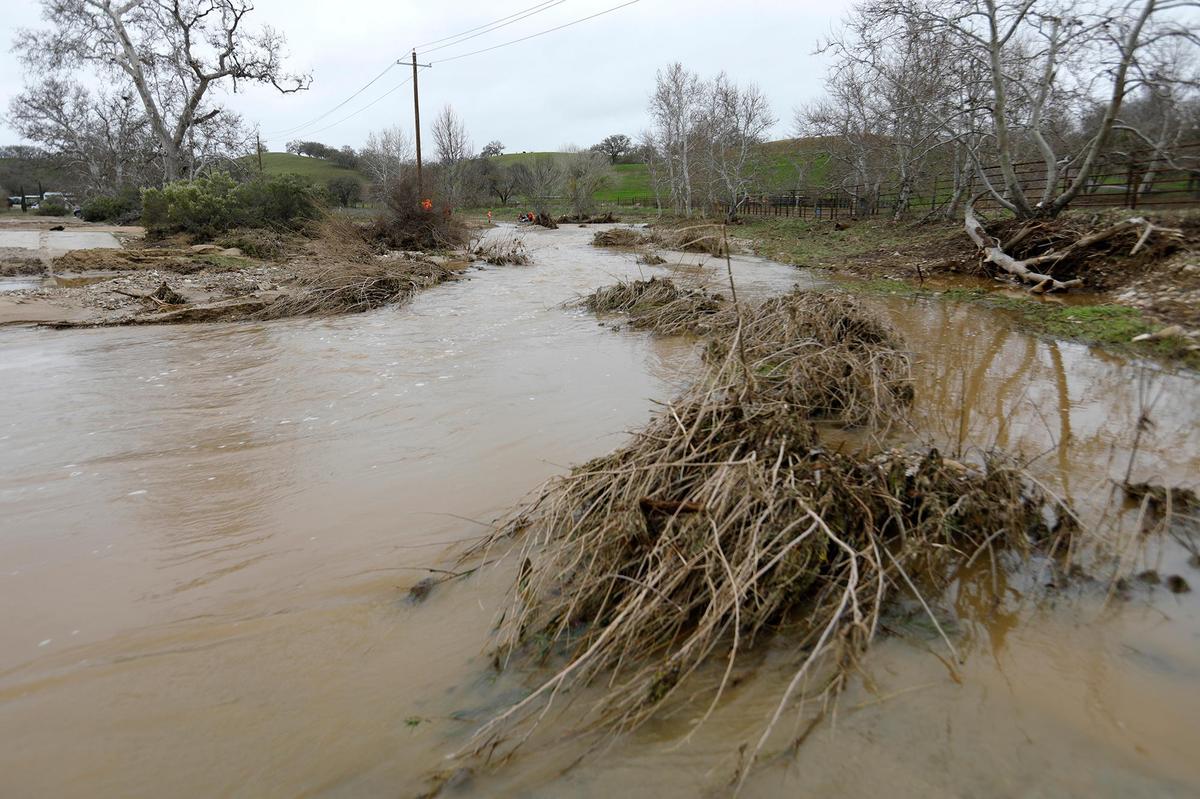 A swollen San Marcos Creek Road flows on Jan. 11, 2023, near the spot where 5-year-old Kyle Doan was swept away in San Miguel on Monday.