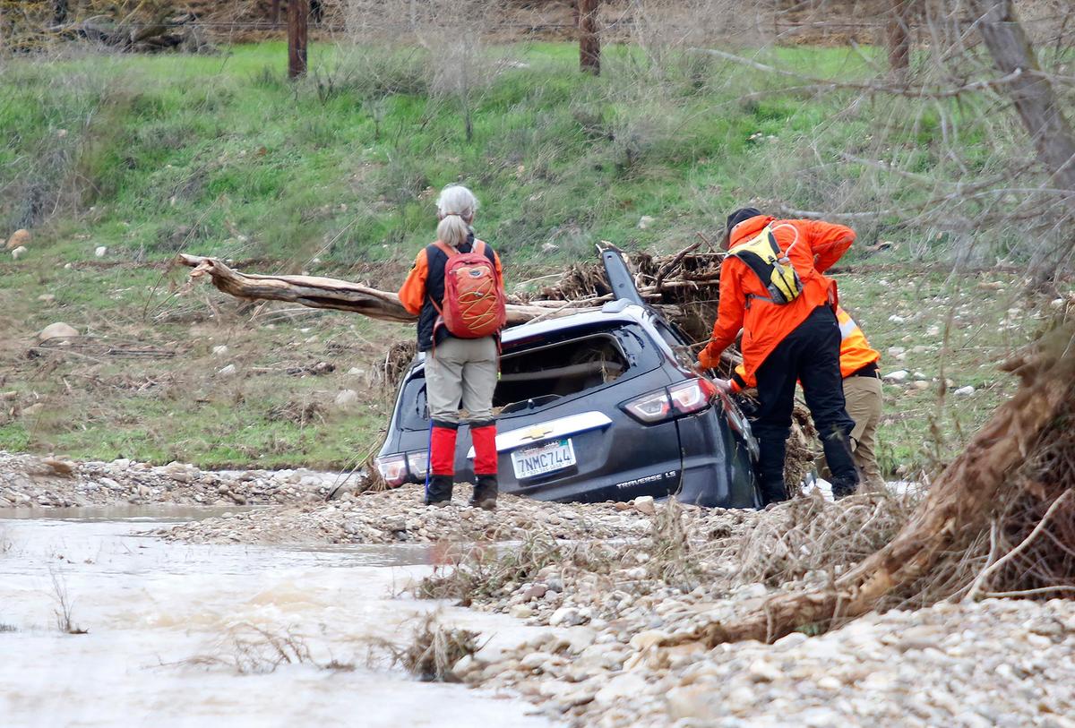 Searchers examine the car that was inundated by floodwaters in San Marcos Creek on Monday, Jan. 9, 2023, before 5-year-old Kyle Doan was swept away by floodwaters in San Miguel