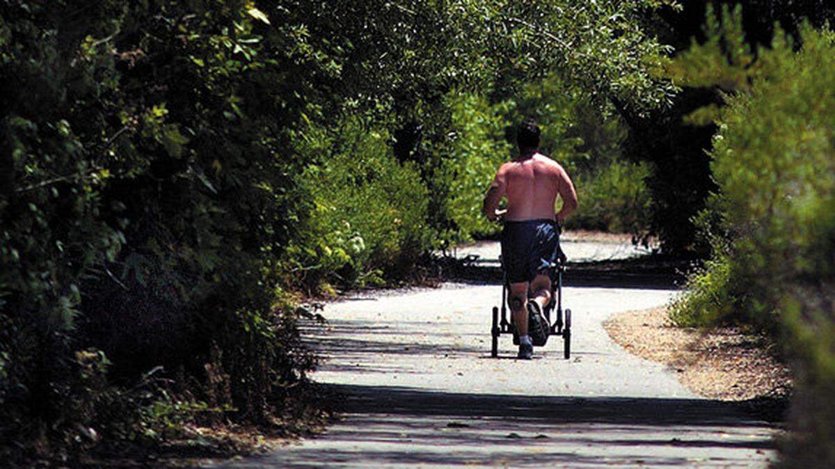 A runner pushes a jogging stroller as he makes his way along the Bob Jones trail in Avila Beach.