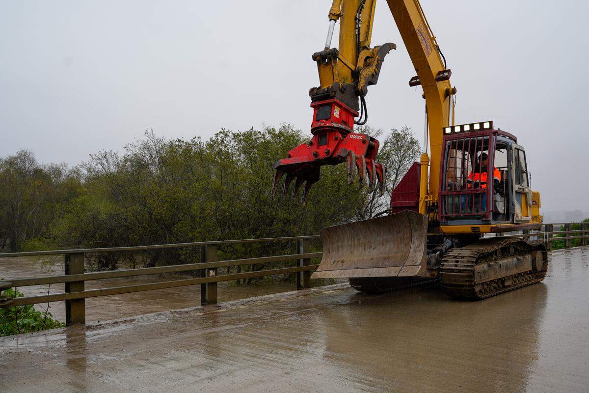 An excavator vehicle crosses the Arroyo Grande Creek Levee during the rainstorm on March 10, 2023.