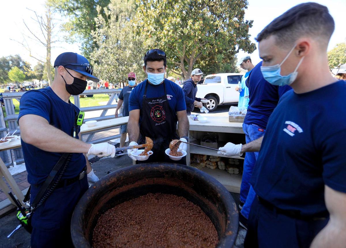 Paso Robles firefighters Justin Ludwig, left, Josh Ruiz and Noah Munds dish out beans at Pioneer Day in Paso Robles on Saturday, Oct. 9, 2021. The parade was canceled and other usual festivities curtailed in 2020 due to the pandemic, and they returned fully this year.