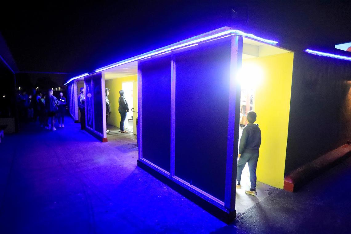 The Sunset Drive-in is one of 16 drive-in movie theaters left in California. People wait in line for popcorn in the night-time glow of the concession booth. (Photo taken June 28, 2019)