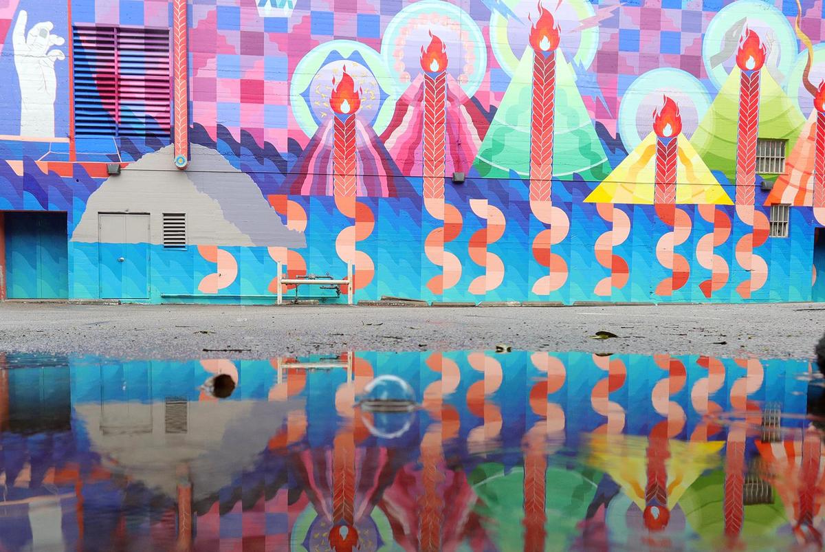 Artist Maria Molteni’s mural of the volcanic peaks on the wall behind the Fremont Theater is reflected in a puddle as light rain falls in downtown San Luis Obispo on Dec. 9, 2021.