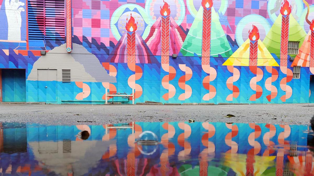 Artist Maria Molteni’s mural of the volcanic peaks on the wall behind the Fremont Theater is reflected in a puddle as light rain falls in downtown San Luis Obispo on Dec. 9, 2021.