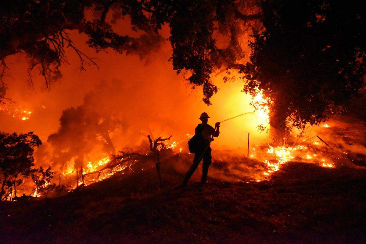 Santa Barbara City firefighter Erik Adair battles flames near a home off Cieneguitas Rd in Santa Barbara Monday night.