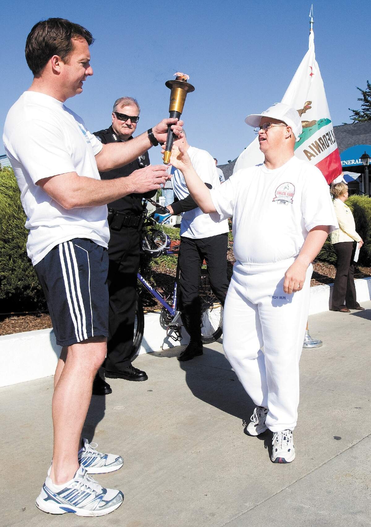 Rick Blankenburg, right, hands the Special Olympics torch to Grover Beach police Officer Kelly Cook in 2011 at the Pismo Coast Village RV Resort as Cook and other members of the department continue the run.