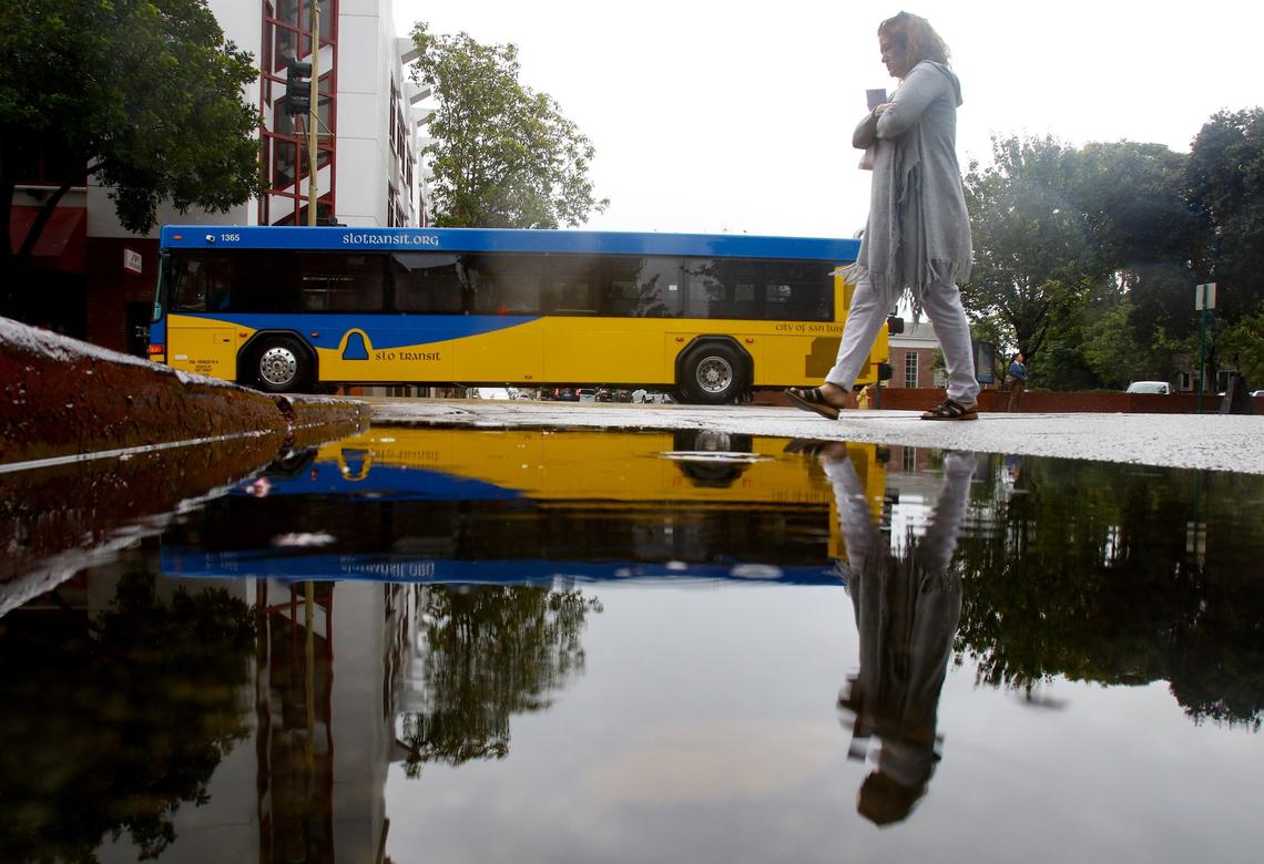 Cynthia Rios walks along Marsh Street at Chorro on Wednesday. The first rain in months brought puddles and umbrellas to the streets of San Luis Obispo County.