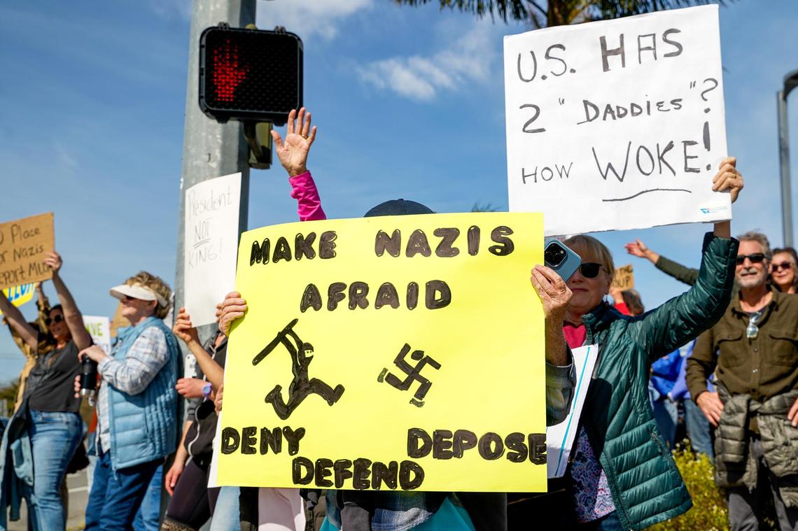 Protesters hold signs and chant to show their opposition to the policies of Donald Trump’s second term in office and Elon Musk’s Department of Governmental Efficiency, on Los Osos Valley Road on Monday, Feb. 17, 2025.