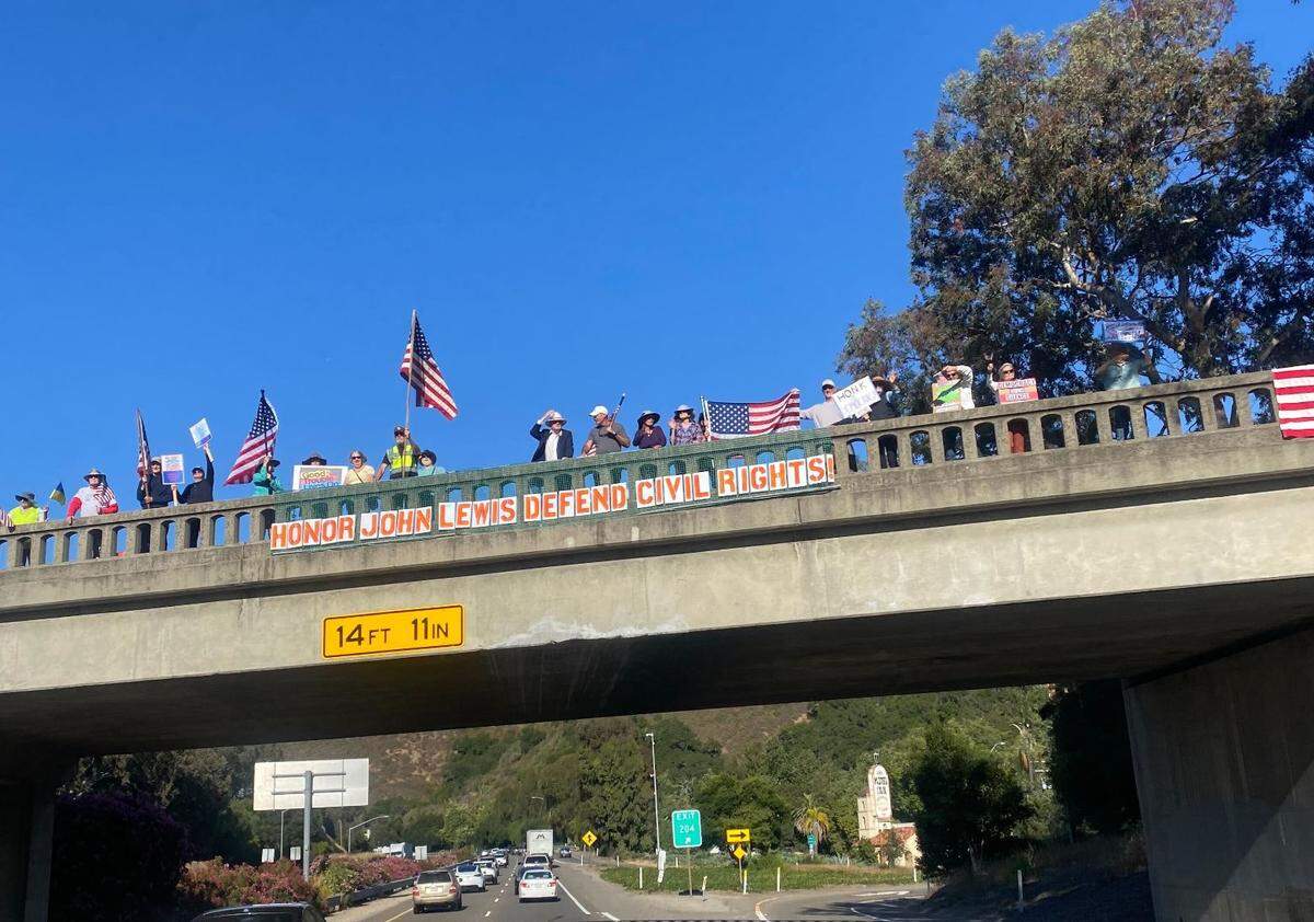 Protesters waved signs atop a bridge in San Luis Obispo on July 17, 2025, as part of a “Good Trouble” protest. Similar protests were held elsewhere in SLO County and nationwide.