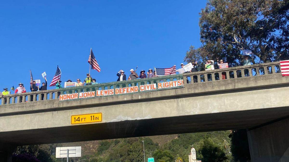 Protesters waved signs atop a bridge in San Luis Obispo on July 17, 2025, as part of a “Good Trouble” protest. Similar protests were held elsewhere in SLO County and nationwide.
