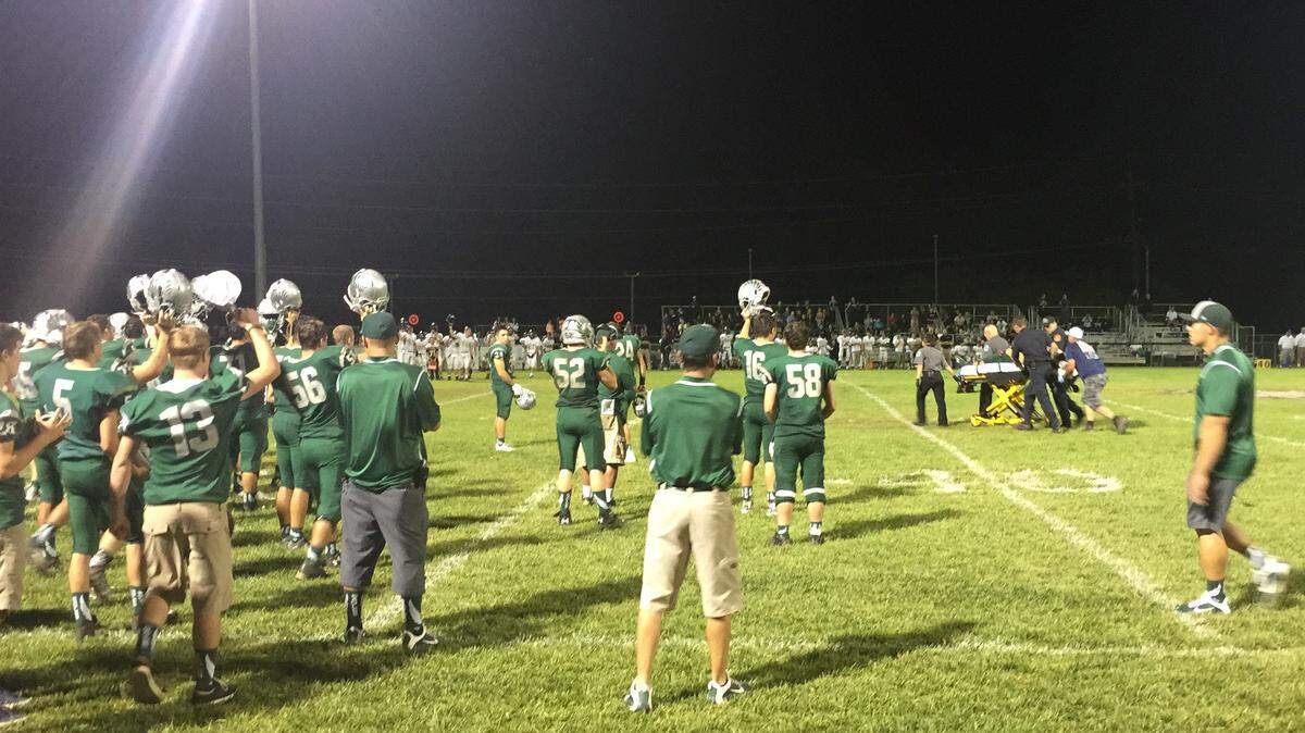 Templeton High School football players hold their helmets high as teammate Isaac Lindsey is taken off the field on a stretcher following an apparent head injury Friday night