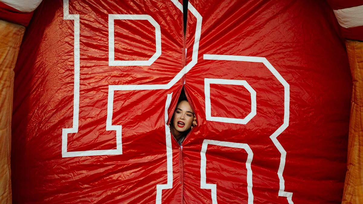 A cheerleader peeks out from inside the entry tunnel for the Paso Robles High School football team before their game against Fresno’s Central High School.
