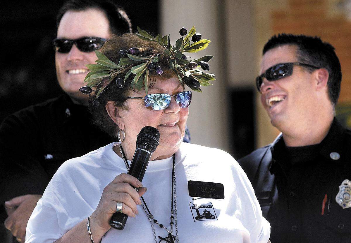Norma Moye, president of the Main Street Association, was wearing a olive  wreath for the festival, introduces the Paso Fire Dept. firefighters Robbie  Smith and Brian Lewis (right) who are about to judge the olive tasting  contest at the First Olive Festival in Paso Robles City Park. Hundreds of  people sampled a myriad of olive oils, olive dishes, wine, and even chocolate  covered olives by Hermann's of Templeton on Aug. 28, 2004.
