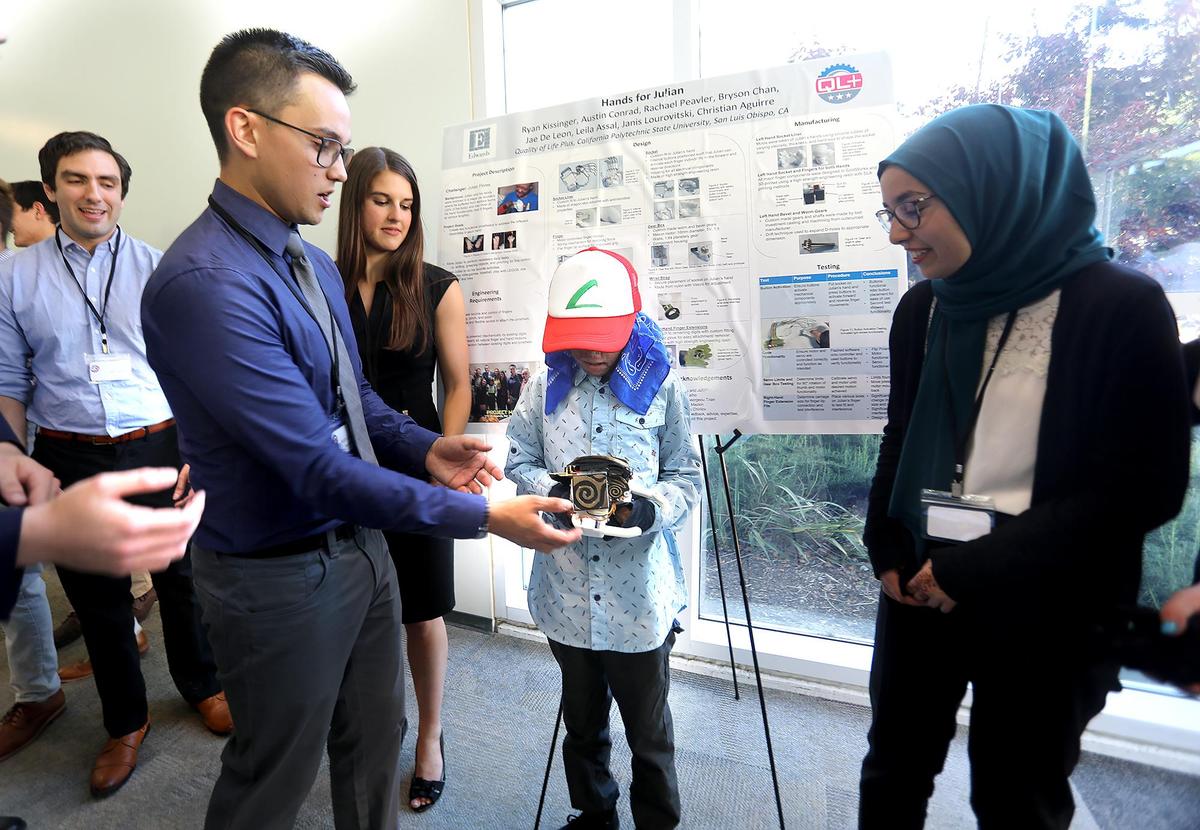 Austin Conrad, center, gives the new prosthetic hand to Julian Reynoso, who lost his hands in a fiery car crash caused by a drunken driver. Other Cal Poly students involved in the project were Jae DeLeon, rear left), Rachael Peabler, rear center, and Leila Assal, right.