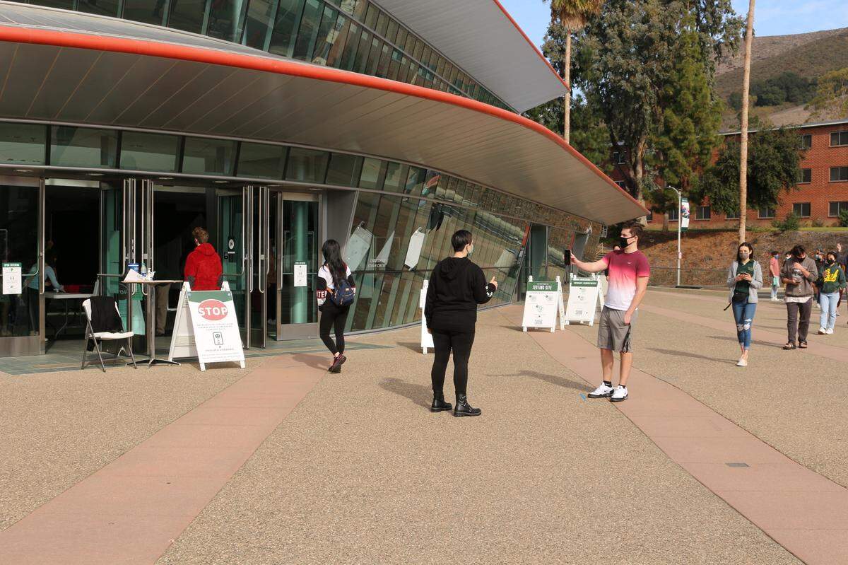 A student shows a Cal Poly worker his phone before being allowed into the university’s Performing Arts Center to get a test for COVID-19 on Jan. 3, 2021.