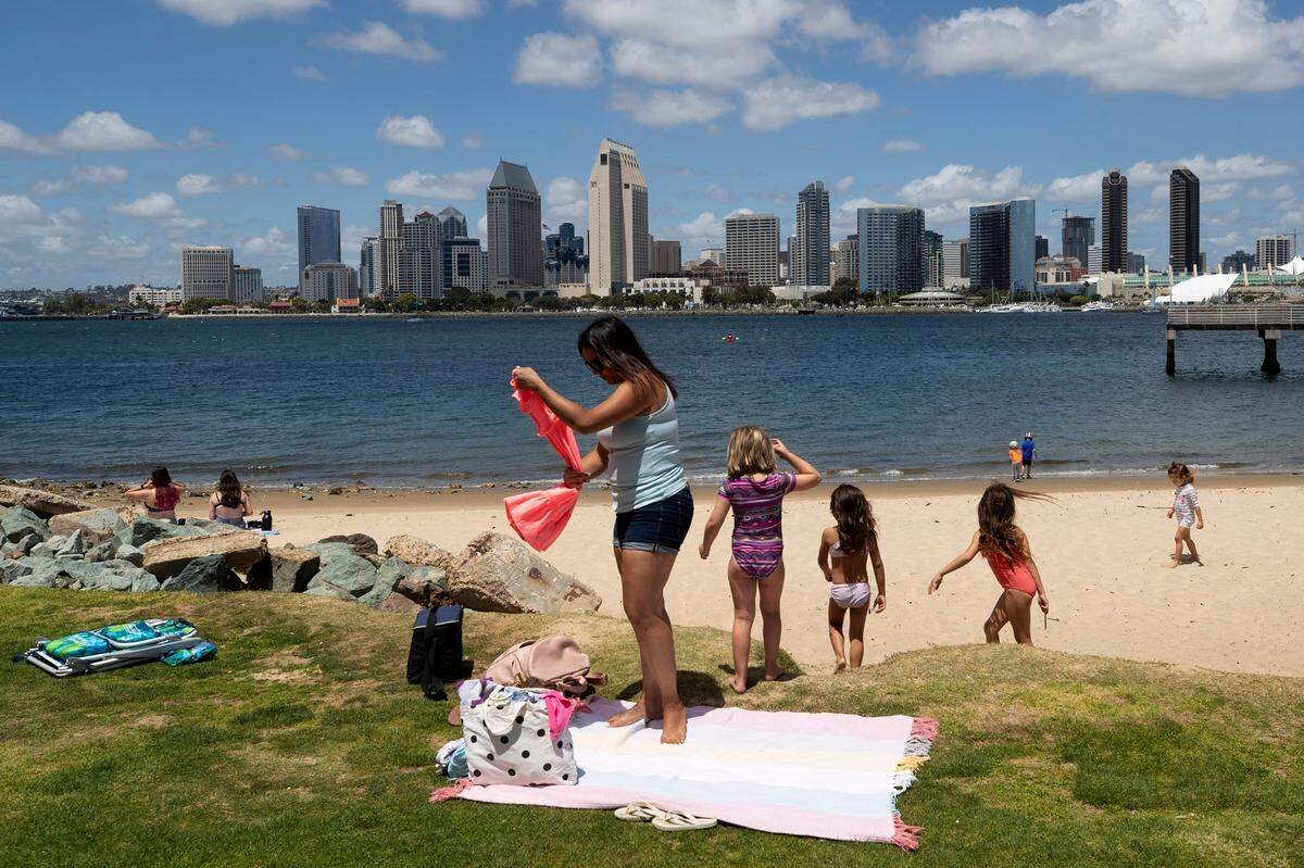 A family sets up at a beach looking out toward the San Diego skyline in Coronado on May 19, 2020. Coronado Beach is one of the Top 25 Beaches in the United States, according to Tripadvisor.