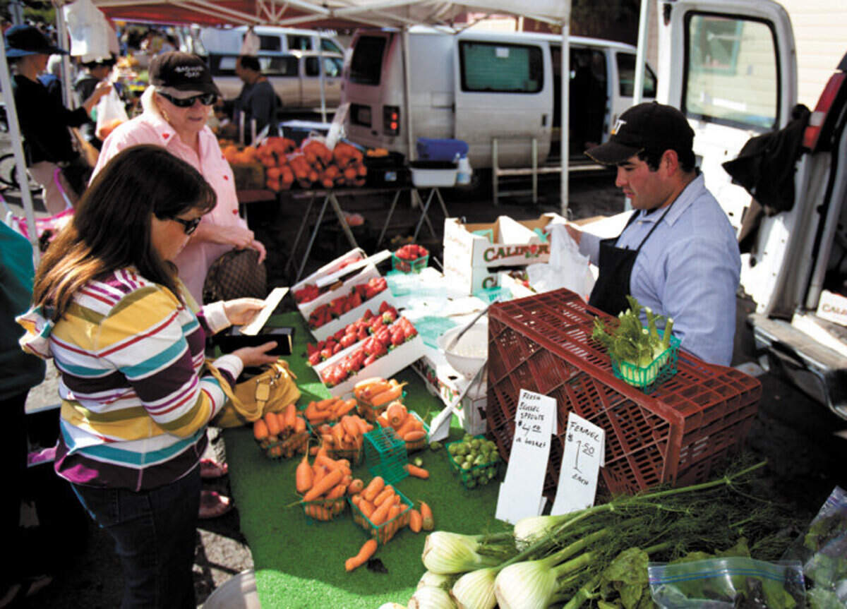 Diane Wiley purchases fresh produce from a stand at the Arroyo Grande Farmers Market.
