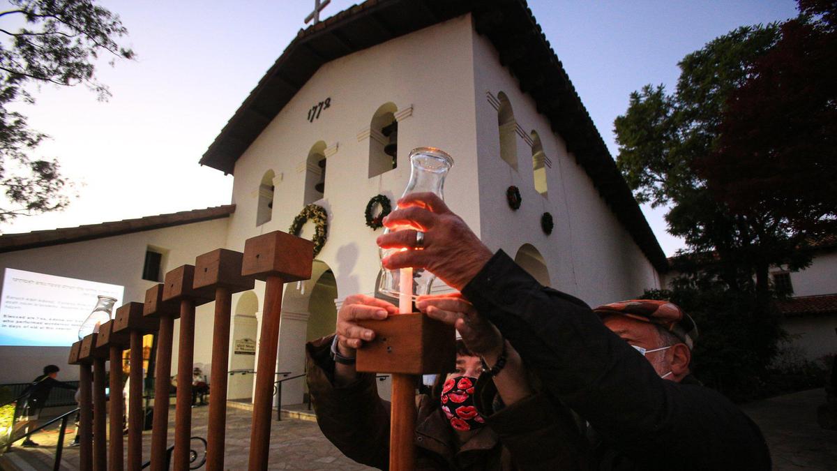 Gail Schwartz and Irwin Joseph place a chimney globe over the shamash or helper candle that lights the others. The JCC Federation of San Luis Obispo County will celebrate the first night of Hanukkah with a candle lighting ceremony in Mission Plaza on Dec. 18, 2022.