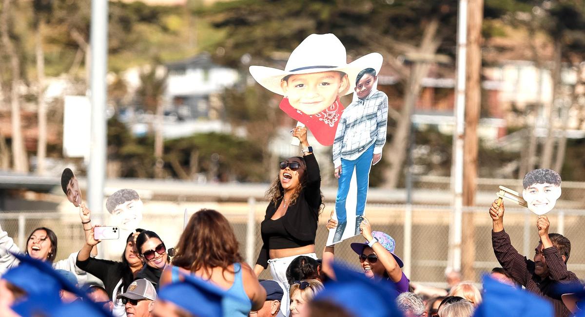 At Morro Bay High School, 180 grads were honored Thursday evening in a ceremony at the school’s football field. Family members hold up large photos of their students.