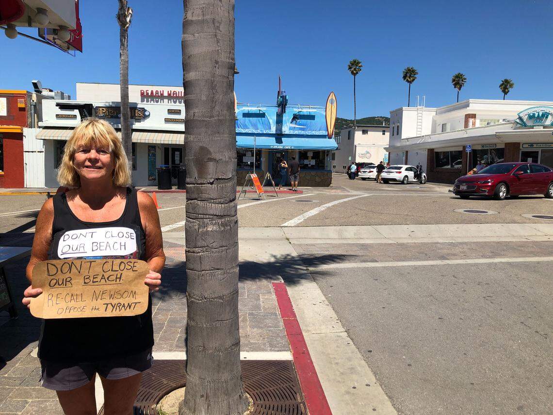 Molly Johnson of Arroyo Grande walked through Pismo Beach Thursday with a sign that read: “Don’t close the beach. Recall Newsom. Oppose the Tyrant.”
