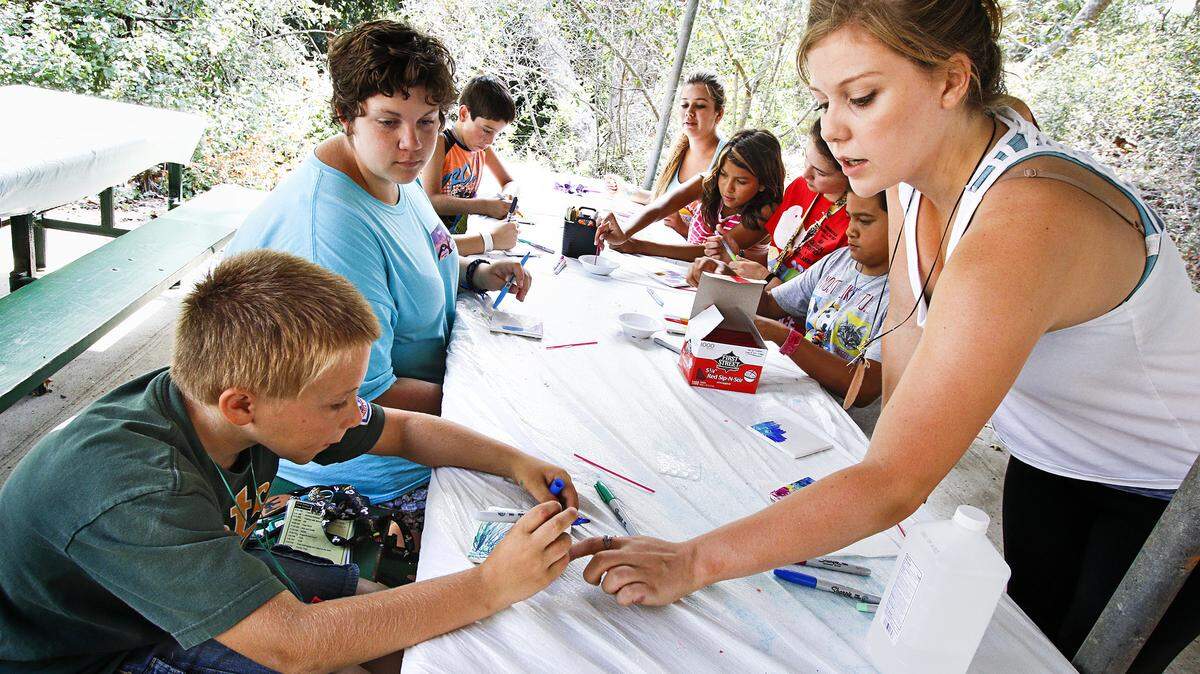 Austin Hall, 9, left, gets some instruction from Erica Mundell-McGilvray during a tie-dye tile-making class at Camp Hapitok.