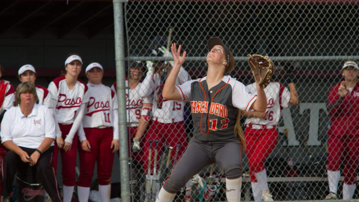 Atascadero’s Shelby Moody gets under a pop-up as the Paso Robles dugout looks on.