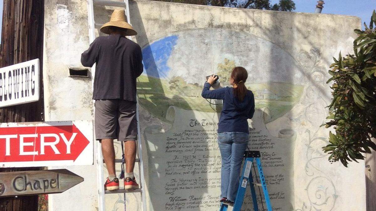Art restorer Phillip Aguirre, at left, and his wife-assistant Mary Aguirre work together in November to begin the process of bringing a 50-year-old Harmony mural back to life. They expect to continue the restoration in January.