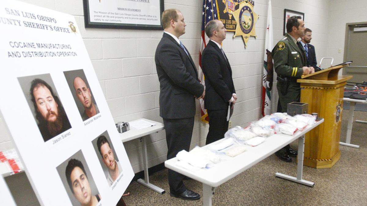 Law enforcement authorities hold a news conference Tuesday on a recent drug-trafficking investigation that resulted in the seizure of cocaine, seen on the near table, and guns, on the far table.