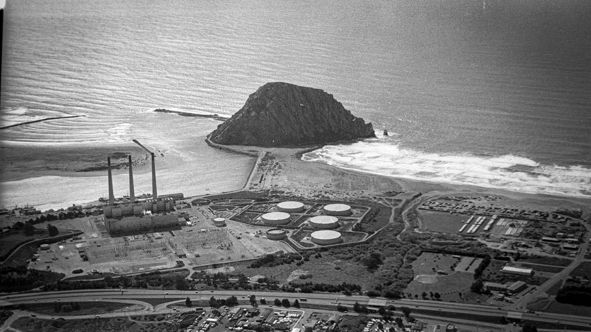 This aerial photo shows PG&E power plant was still in operation and had fuel oil tanks in 1984. This was before the boardwalk was built to Morro Rock. Also seen harbor mouth with jetties, and Highway 1 in foreground. Reporter Brooks Townes took a flight over coastal areas from Morro Bay to Avila Beach on Feb. 22, 1984.