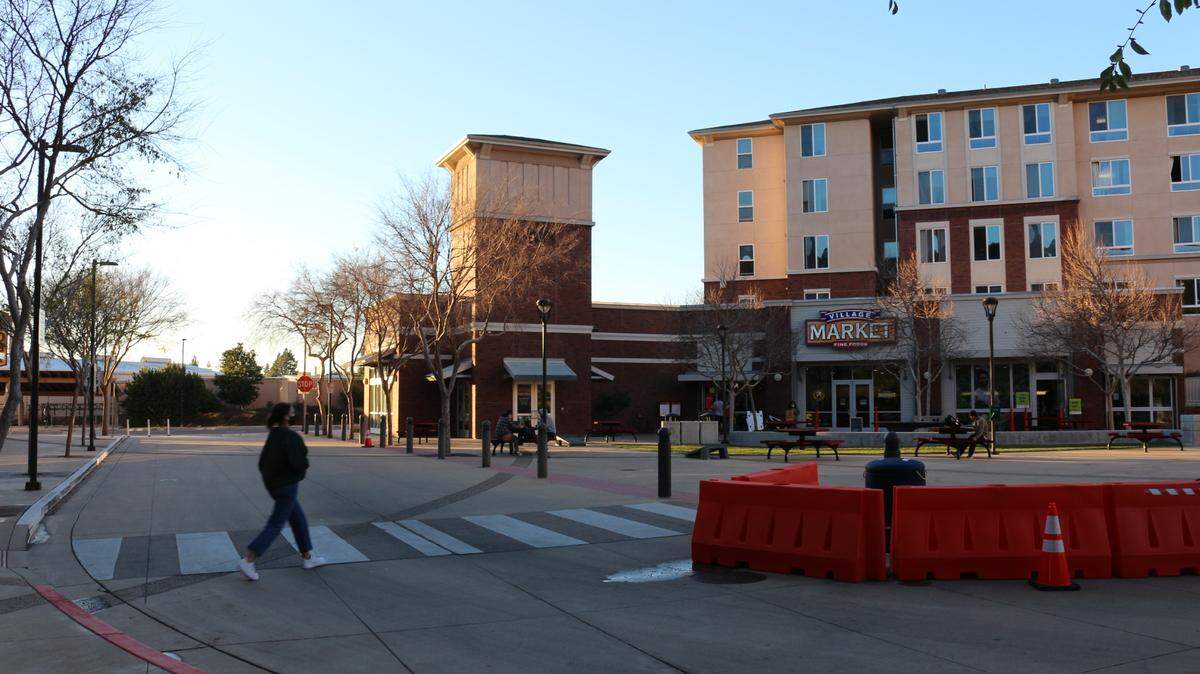 A student walks across Canyon Circle near the entrance of Cal Poly’s Poly Canyon Village apartments.