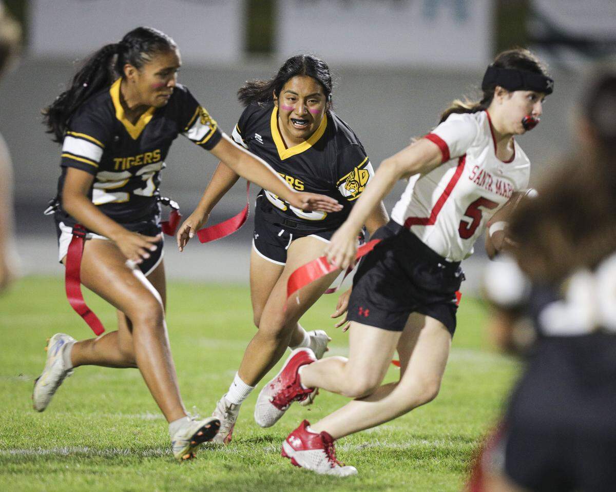 Sydney Rodriguez, left, and Darla Sebastian Martinez pursue Saints quarterback Nevaeh Hope. San Luis Obispo beat Santa Maria 51-6 in a girl's flag football game seen here on Oct. 16, 2025.