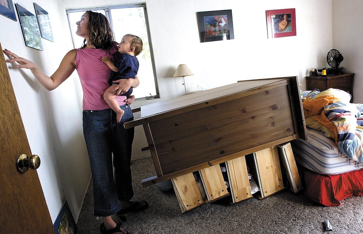 Liza Fierro, along with her 9 month-old son Diego, inspects her bedroom where her dresser was knocked over and some pictures fell off the wall as a result of the 6.0 magnitude earthquake in 2004 near Parkfield, Calif.