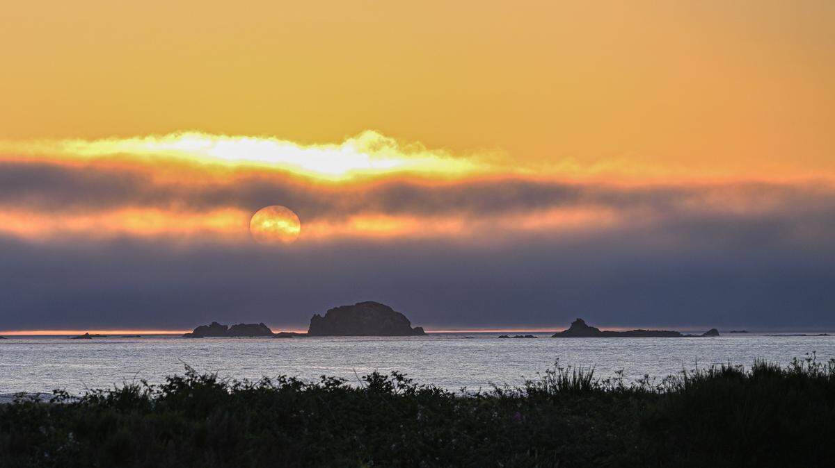 The sun sets over the marine layer along the Oregon coastline