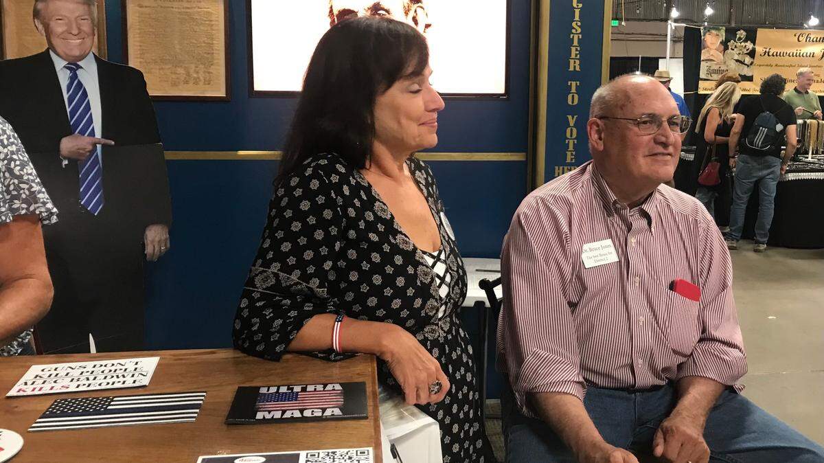 Dr. Bruce Jones, right, a candidate for San Luis Obispo County supervisor, greets visitors to the Mid-State Fair in Paso Robles under the gaze of a Donald Trump cutout in the background.