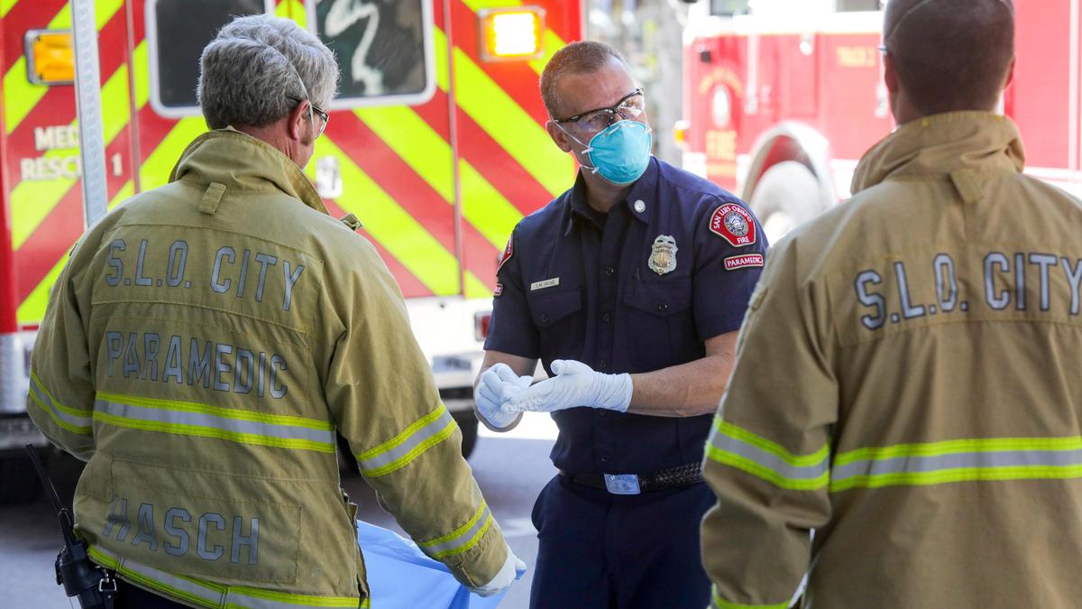 San Luis Obispo city Fire Captain Shayne Skove performs the cleaning protocol after helping someone exhibiting symptoms consistent with coronavirus. Other firefighters are ready to dispose of used protective equipment.