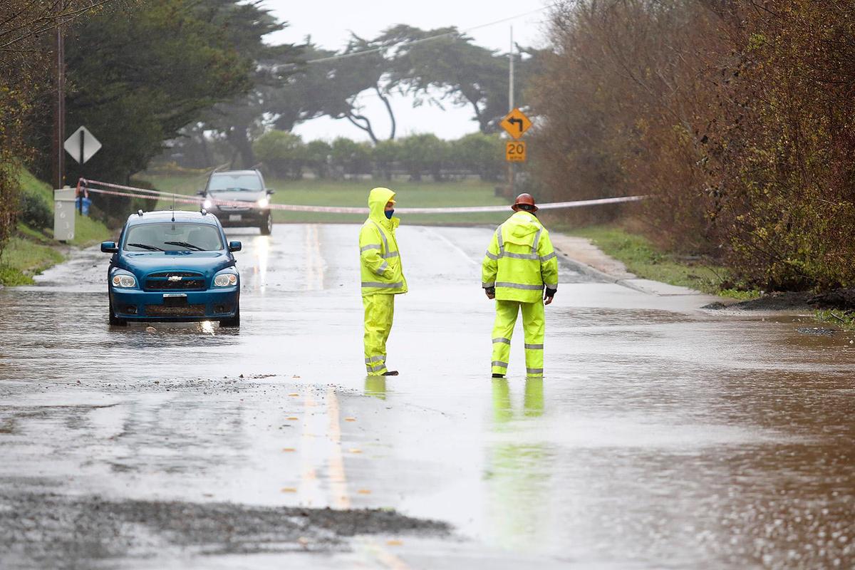 SLO County workers assess the flooding on Windsor Boulevard near Santa Rosa Creek on Thursday morning in Cambria as a huge storm dumped rain across the area.
